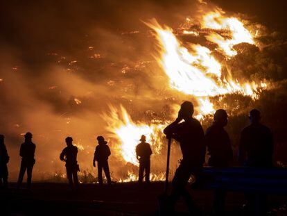 Forest firefighters and local residents observe the blaze last August in Navalacruz, Ávila.