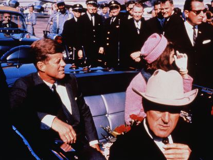 Texas Governor John Connally adjusts his tie (foreground) as US President John F Kennedy (left) & First Lady Jacqueline Kennedy (in pink) settled in rear seats, prepared for motorcade into city from airport, Nov. 22, 1963.