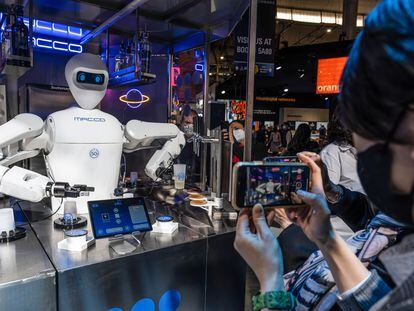 A visitor takes a photo of a Barman 5G waiter robot mixing drinks during the Mobile World Congress 2022.