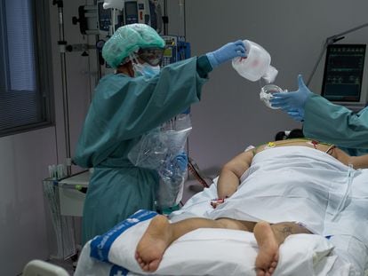Dos enfermeras preparan a una mujer recién ingresada para su estancia en la UCI
