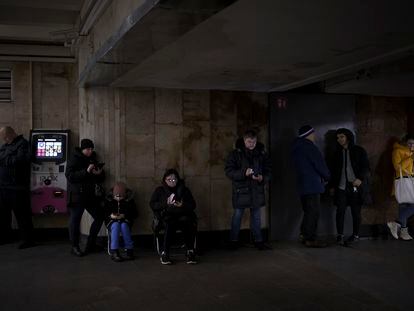 Ukrainians look at their cell phones while taking shelter in a Kyiv metro station during an air raid in December 2022.