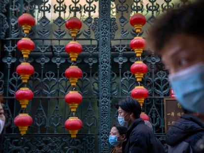 People wearing face masks walk past rows of lanterns at a tourist shopping street in Beijing, Tuesday, Feb. 28, 2023.