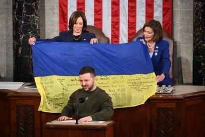 Volodymyr Zelenskiy addresses Congress while Vice President Kamala Harris and then-House Speaker Nancy Pelosi hold the signed flag.