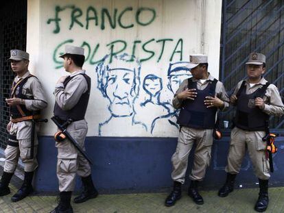 Paraguayan police stand near graffiti accusing Franco of staging a coup.