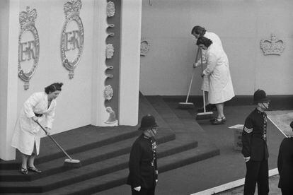 A group of cleaners sweeping the steps leading up to the annexe opposite the west entrance of Westminster Abbey before the coronation of Queen Elizabeth. The annexe is used as a space to host processions before the coronation.