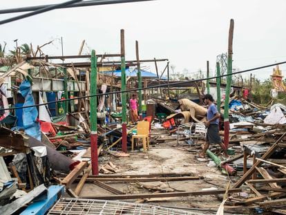 Local residents walk past damaged buildings after Cyclone Mocha in Sittwe township