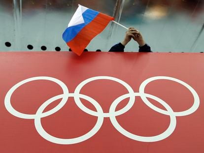 A Russian flag is held above the Olympic Rings at Adler Arena Skating Center during the Winter Olympics in Sochi, Russia on Feb. 18, 2014.