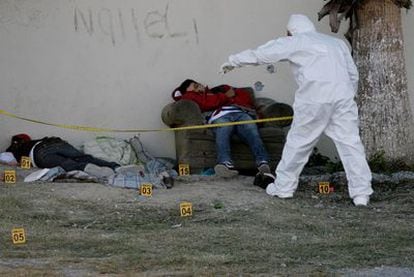 A member of the Mexican police forensics team examines the bodies of two men killed by drug traffickers on the outskirts of Monterrey.