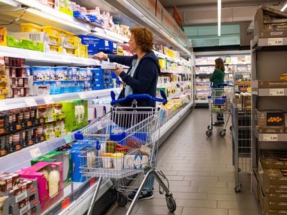 A woman selects refrigerated products in a supermarket.