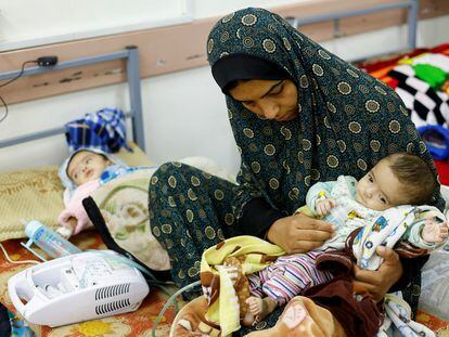 A Palestinian woman with her twin daughters who suffer from malnutrition at a health center in Rafah.