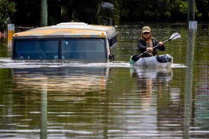 A man paddles a kayak next to a submerged bus in Brisbane, Australia; February 28, 2022