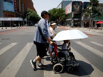 Pedestrians cross a road on a hot day amid an orange alert for heatwave, in Beijing, China June 16, 2023.