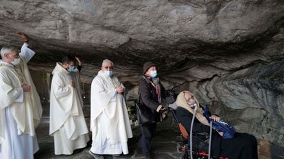 A group of priests accompanies a sick woman in a wheelchair at the entrance to the grotto of the sanctuary of Lourdes in France, where thousands of pilgrims arrive every year in search of a cure for their illnesses.