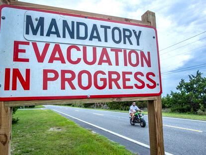 A person rides a bike near a 'mandatory evacuation' sign, as the town prepares for Hurricane Idalia, in Cedar Key, Florida, USA, 29 August 2023.