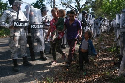 A family from Honduras is flanked by officers of the Mexican National Guard at a road check in Chiapas. 