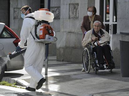 An elderly couple observes a man disinfecting the streets of Vitoria in Spain’s Basque Country on Monday.