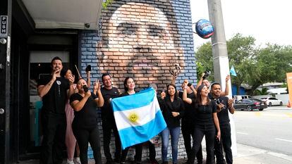 Staff at Miami’s Fiorito Restaurant wave the flag of Argentina in front of a mural of Lionel Messi, on June 7, 2023.
