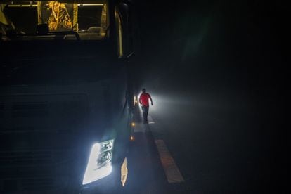 Lázaro Bermejo stops to sleep in a lay-by on a road near Chartres, France. At dawn, he checks the truck in the fog before continuing on his way with a refrigerated trailer full of flowers.