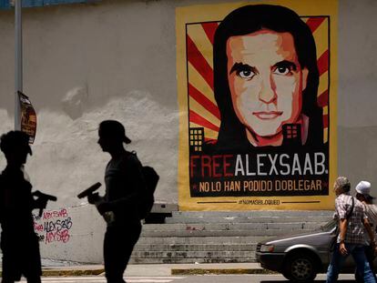Pedestrians walk near a poster of Alex Saab that reads, “Free Alex Saab. They haven't been able to bend him," in Caracas, Venezuela.