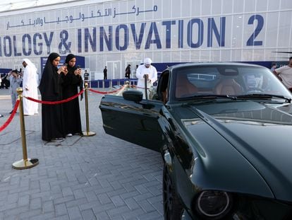 People take pictures of a displayed electric car on the sidelines of the United Nations Climate Change Conference (COP28) in Dubai, United Arab Emirates, December 10, 2023.