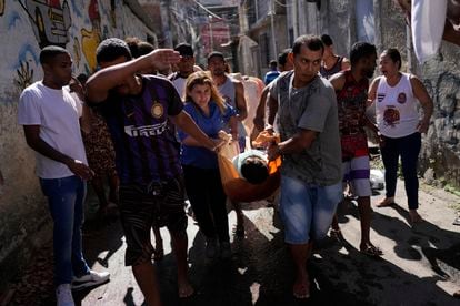 People carrying a dead body following a police raid in a favela complex in the north of Rio de Janeiro (Brazil).
