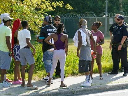 Residents talk with Jacksonville police officers near the scene of a mass shooting at a Dollar General store, Saturday, Aug. 26, 2023, in Jacksonville, Fla.