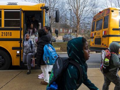 Rock Creek Forest Elementary School students exit a diesel bus before attending school, Friday, Feb. 2, 2024, in Chevy Chase, Md. At right is an electric school bus.