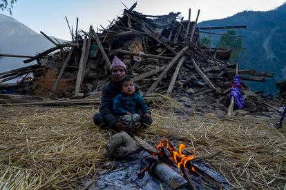 A man and a child sit in front of an earthquake damaged house in Jajarkot district, northwestern Nepal, Sunday, Nov. 5, 2023.