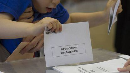 A young boy places a voting slip in Barcelona.