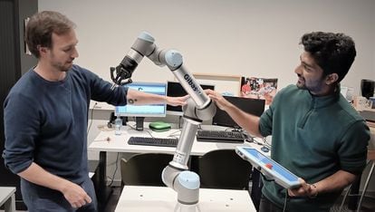 Pablo Lanillos, scientific coordinator of METATOOL (left) and postdoctoral researcher Ajith Anil Meera with one of their industrial robots.
