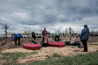 A priest officiates a funeral for several victims killed after attacks by Russian troops in the city of Bucha, on April 18.