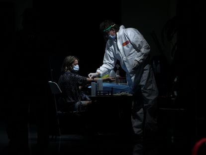 A health worker takes a blood sample from a woman at the Arts Center Auditorium in Arroyomolinos, Madrid.