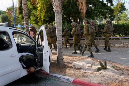 Israeli soldiers in Sderot pass by the body of a civilian shot in his vehicle.