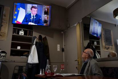 A man at a bar watches French President Emmanuel Macron speaking during an interview with journalists on television in Marseille, southern France, on March 22, 2023.