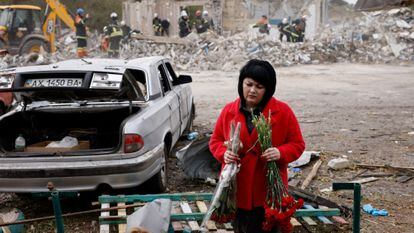 A woman lays flowers at the site of Thursday's attack in Hroza, in Kharkiv province. 