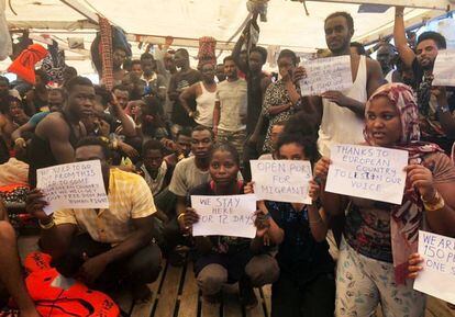 The rescued migrants hod up signs calling for help.