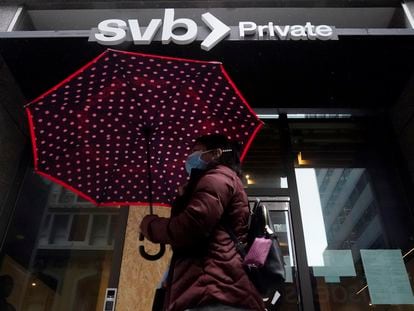 A pedestrian carries an umbrella while walking past a Silicon Valley Bank Private branch in San Francisco, Tuesday, March 14, 2023.