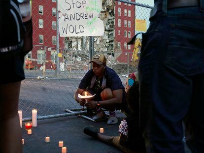 Raquel Sipp kneels with a candle at the scene of where an apartment building partially collapsed two days earlier, in Davenport, Iowa, Tuesday, May 30, 2023.