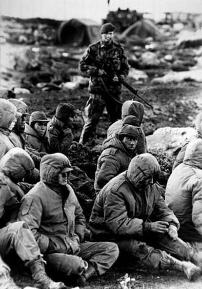 A Royal Navy officer guards Argentinean prisoners during the 1982 Falklands War.