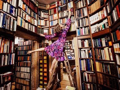 A woman looking for a book in a bookshelf.