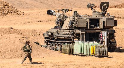 An Israeli soldiers walks past a M109-type self-propelled howitzer, upgraded version for IDF called 'Doher