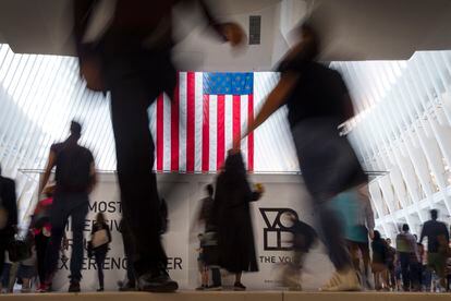 People walk past an American flag inside the Oculus, part of the World Trade Center transportation hub