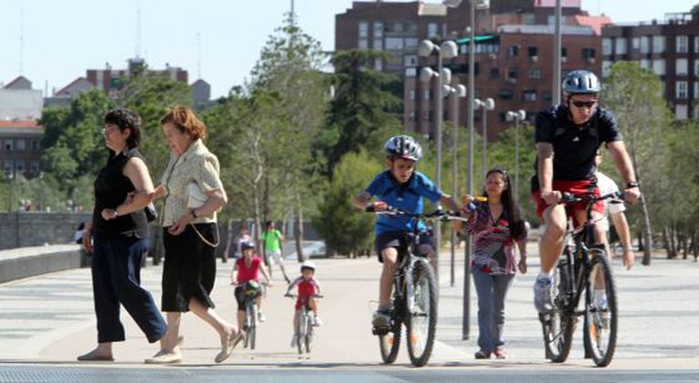 Cyclists mingle with pedestrians in the Madrid Río park in the capital. But should all bike users have to wear helmets?