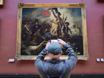 A visitor photographs the 'Liberty Leading the People' painting in the Louvre.