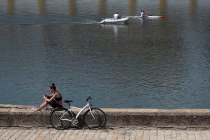 A woman sits by the Guadalquivir river in Seville, Andalusia, which will move to Phase 3 on Monday.