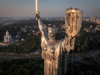 Workers install the Ukrainian coat of arms on the shield in the hand of the country's tallest stature, the Motherland Monument, after the Soviet coat of arms was removed, in Kyiv, Ukraine, Sunday, Aug. 6, 2023.