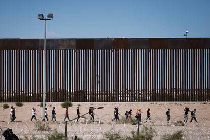 A group of people walk in front of the border wall between Ciudad Juárez (Chihuahua) and El Paso (Texas).
