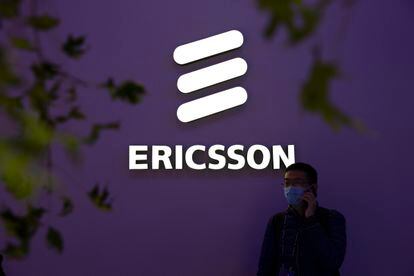 A man wearing a face mask talks on his smartphone near a booth from Swedish technology firm Ericsson at the PT Expo in Beijing, Wednesday, Oct. 14, 2020.