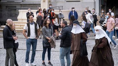 Two masked nuns walk by a group of tourists in Seville on Monday.