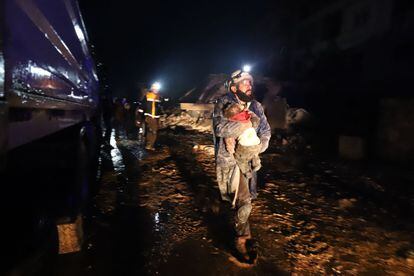 A member of the Syrian civil defence, known as the White Helmets, carries a child rescued from the rubble following an earthquake in the town of Zardana in the countryside of the northwestern Syrian Idlib province.